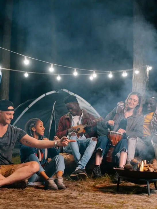 Friends enjoying a campfire at night on a camping trip, showing how well-organized trips create fun and stress-free moments together.