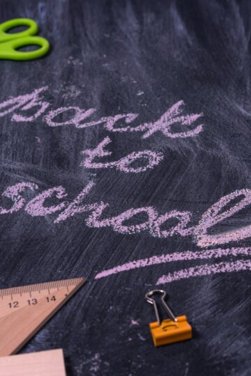 Back-to-school tips for parents illustrated with chalk writing “Back to School” on a blackboard surrounded by school supplies like scissors, chalk, ruler, and alarm clock