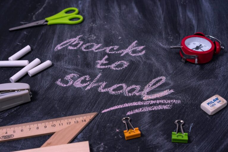 Back-to-school tips for parents illustrated with chalk writing “Back to School” on a blackboard surrounded by school supplies like scissors, chalk, ruler, and alarm clock