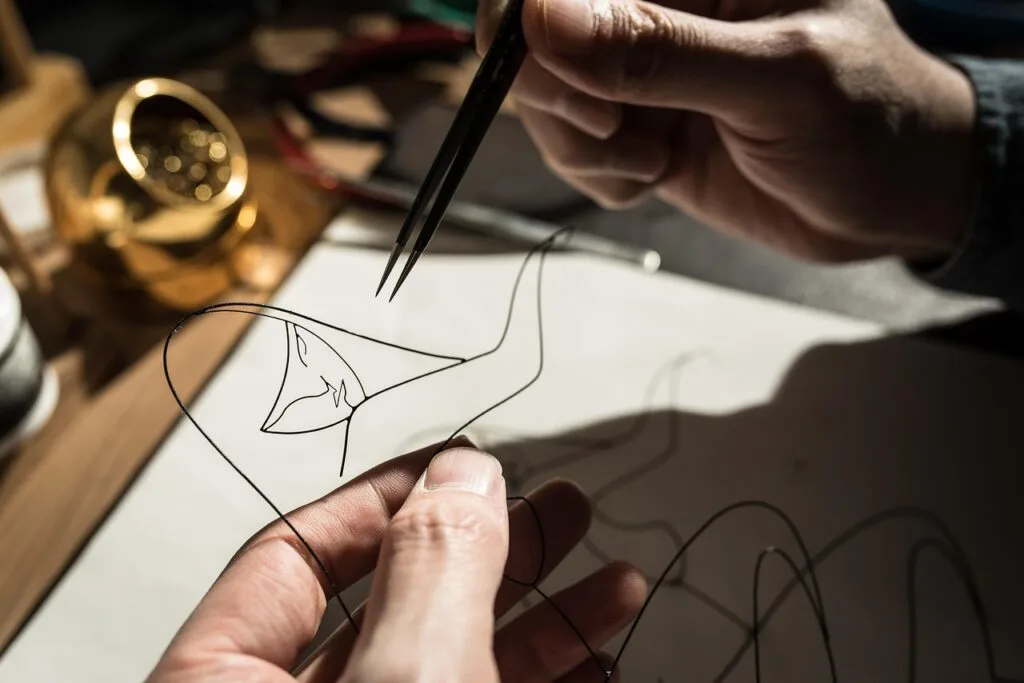A man crafting with wire crafting the shape of a woman