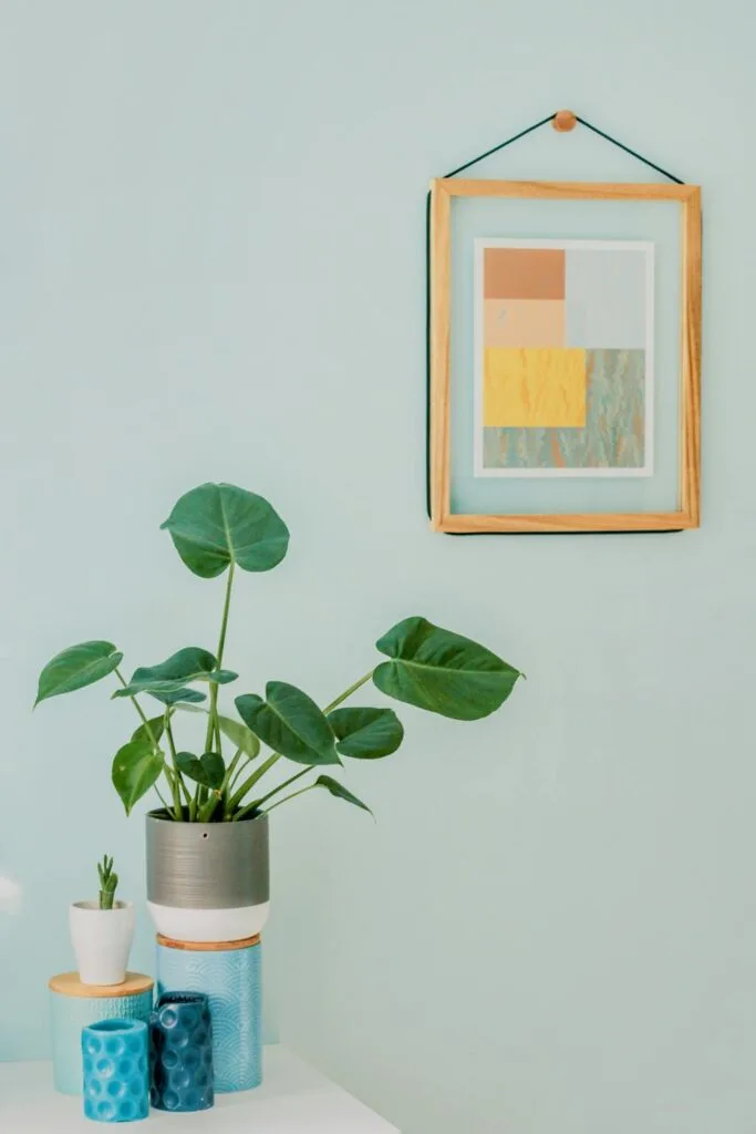 Small decorative table with a plant and vases, placed against a wall featuring framed artwork&mdash;an example of creative wall decor ideas.

