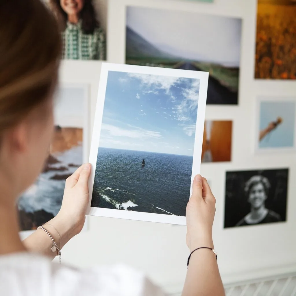 A woman haning pictures on a gallery wall in her home