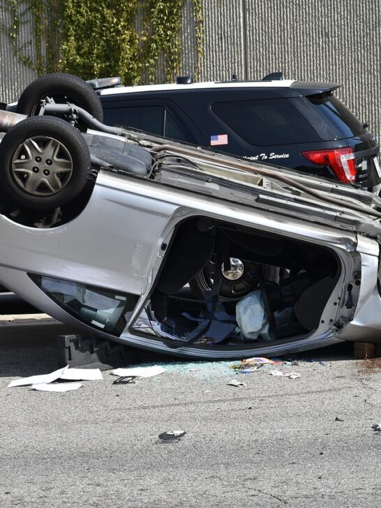A silver sedan laying on its roof after flipping into another car. This is a good example of why going solo on a car crash claim is not a good idea.