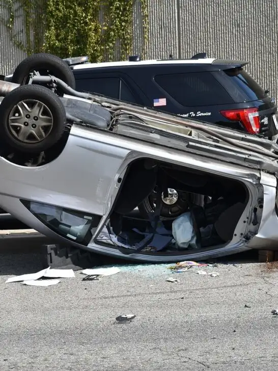 A silver sedan laying on its roof after flipping into another car. This is a good example of why going solo on a car crash claim is not a good idea.