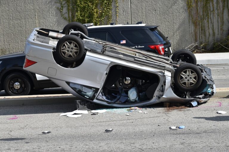 A silver sedan laying on its roof after flipping into another car. This is a good example of why going solo on a car crash claim is not a good idea.