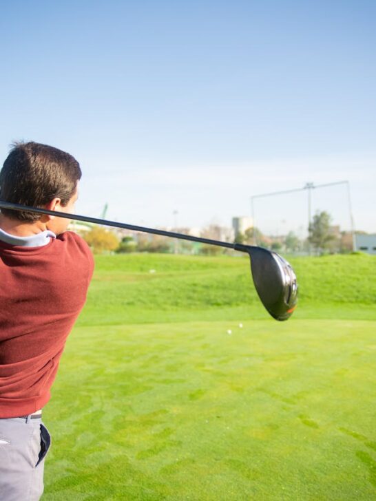A man mid-swing wearing the proper golf course attire