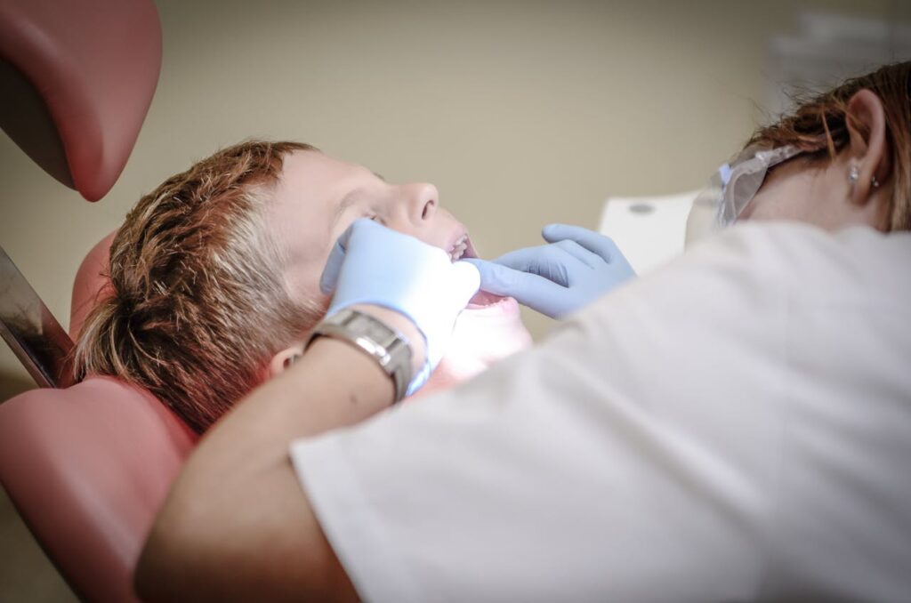 Dentist examining young boy's teeth during checkup, highlighting how oral health affects child development.