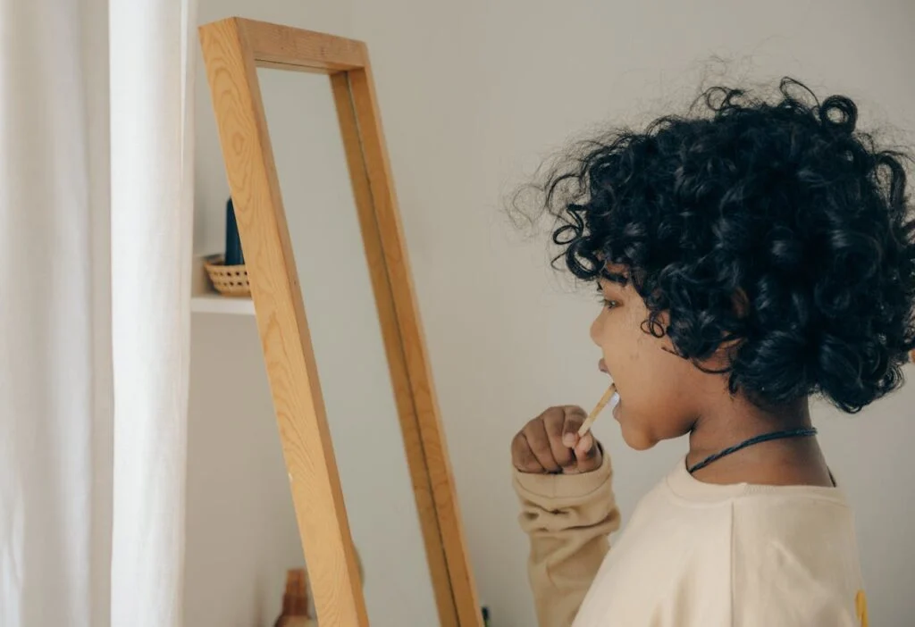 A child standing in front of a mirror  brushing their teeth.