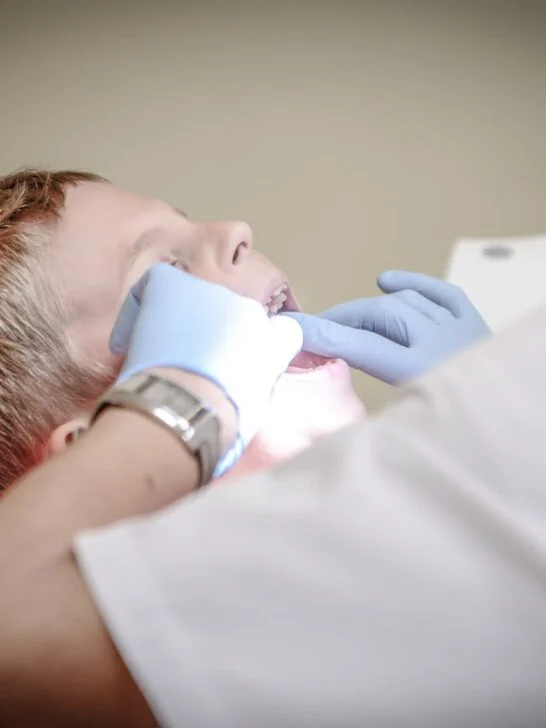 Dentist examining young boy's teeth during checkup, highlighting how oral health affects child development.