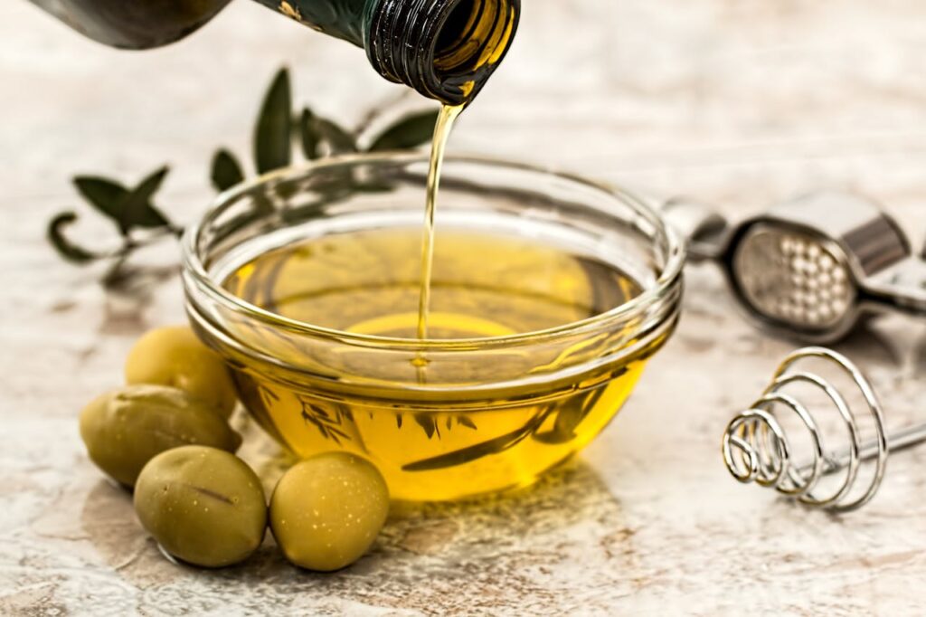 Olive oil being poured into a clear bowl representing the many benefits of olive oil beyond cooking