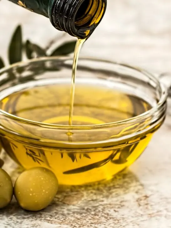 Olive oil being poured into a clear bowl representing the many benefits of olive oil beyond cooking