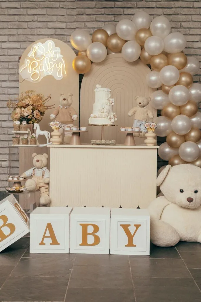 gold color themed baby shower layout with toys and treats