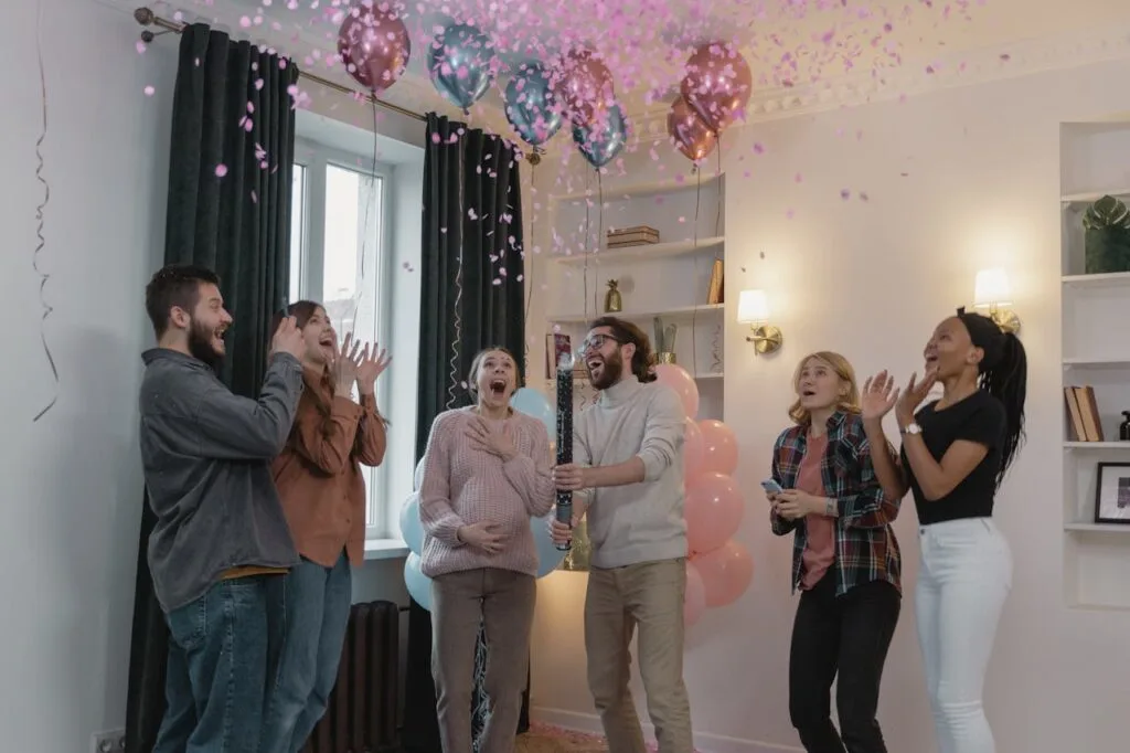 People at a gender reveal party clapping as confetti falls