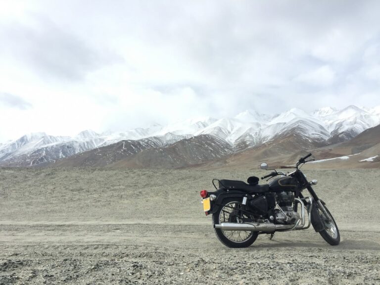 A classic black motorcycle parked on a rugged mountain road with snow-capped peaks in the background — perfect for choosing the right motorcycle for adventurous rural rides