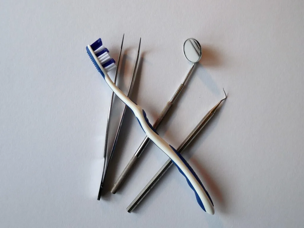Flat lay of toothbrush and dental instruments on a white background; perfect visual for family dental care tips.