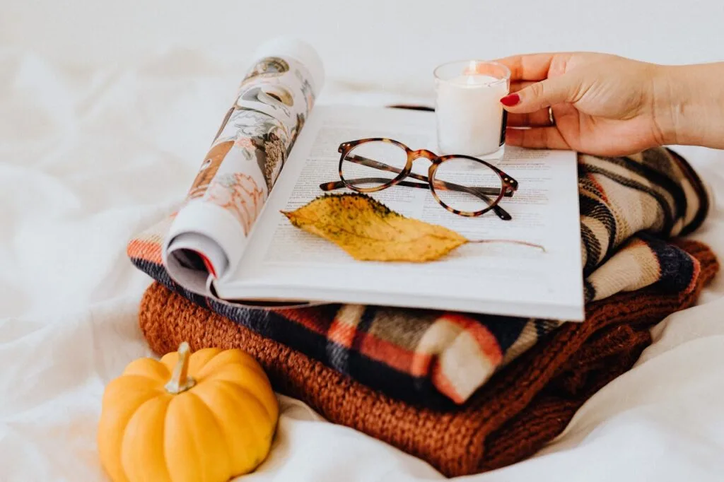 Cozy autumn scene with tortoiseshell frames resting on a book, plaid blanket, and pumpkin, perfect example of how to get glasses with a prescription styled at home.