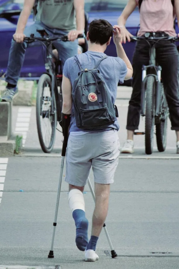 Person using crutches with a leg cast, highlighting the long-term health effects of road accidents.