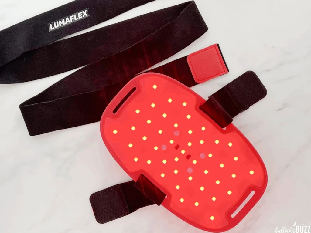 Lumaflex Essential red light therapy device turned on, showing dual-chip LEDs glowing for pain relief and recovery