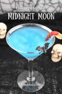 Close up picture of a sparkling blue Midnight Moon Halloween Cocktail with bat and gummy worm garnishes