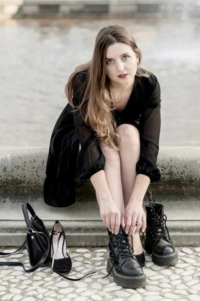 a woman sitting down and putting on combat boots