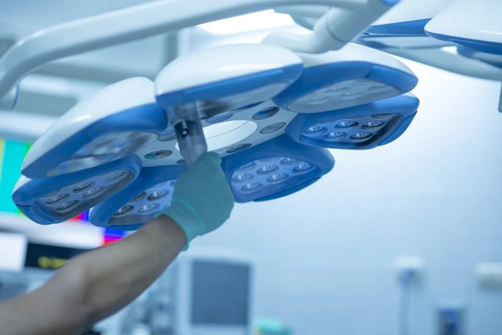 Close-up of a surgeon adjusting bright operating room lights before a procedure.