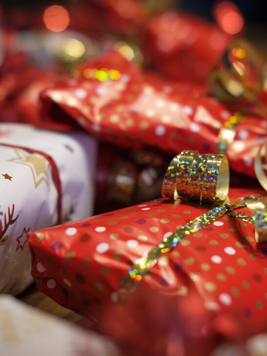 Brightly wrapped holiday presents in red and white paper with gold ribbons, perfect inspiration for creative personalized gift ideas.