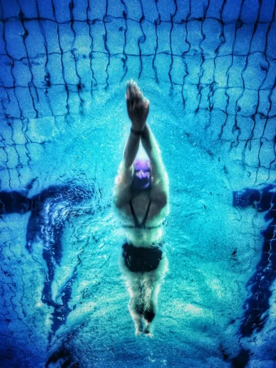 Underwater view of a swimmer diving with arms extended, showcasing focus, clarity, and the benefits of sports vision training in competitive performance.