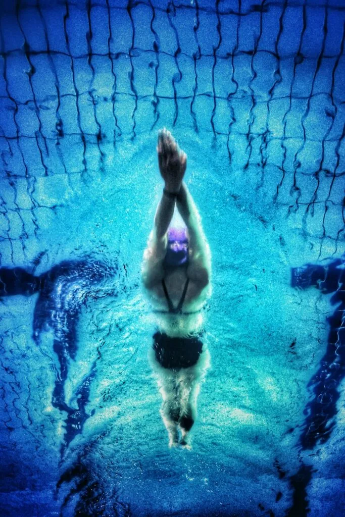 Underwater view of a swimmer diving with arms extended, showcasing focus, clarity, and the benefits of sports vision training in competitive performance.