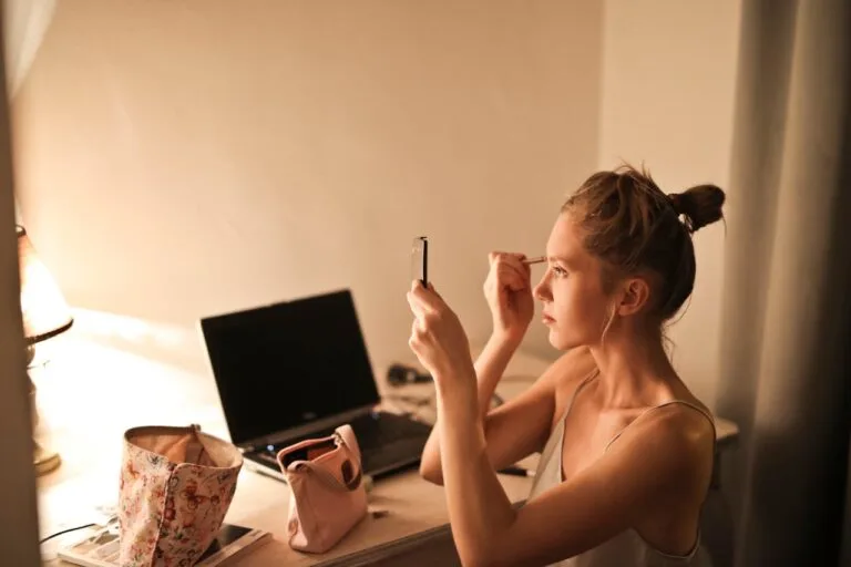Woman using a small makeup pouch at her vanity, showing how the best makeup bag keeps beauty essentials organized for easy everyday routines