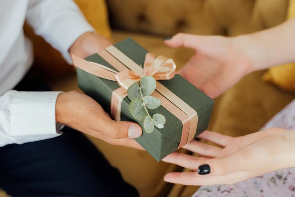 A person handing a gift to another representing personalized gift ideas