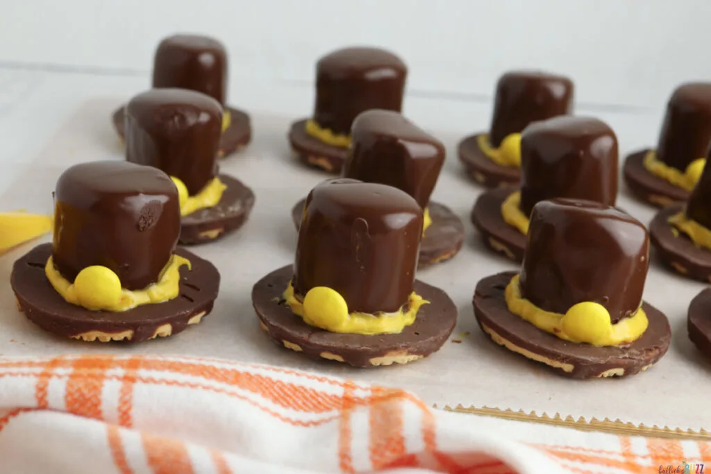 Piping yellow melted candy around the base of marshmallow Pilgrim hats