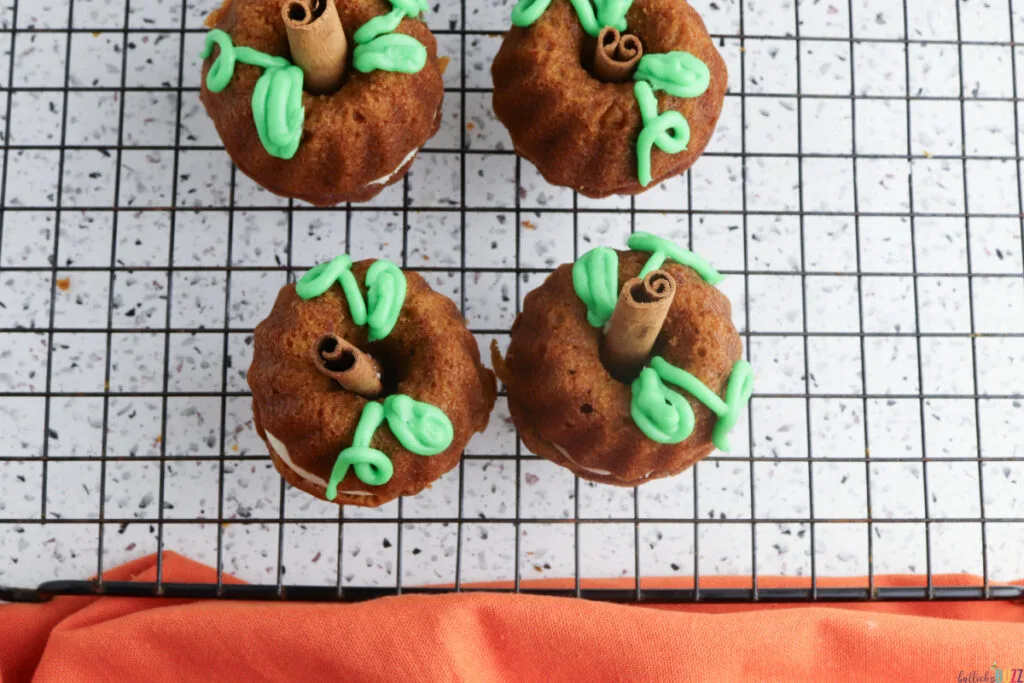 Decorating pumpkin cakes with green frosting vines and leaves