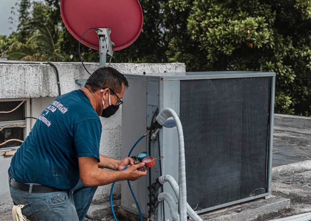 Professional contractor testing refrigerant levels while preventing common air conditioner replacement mistakes on a rooftop system.