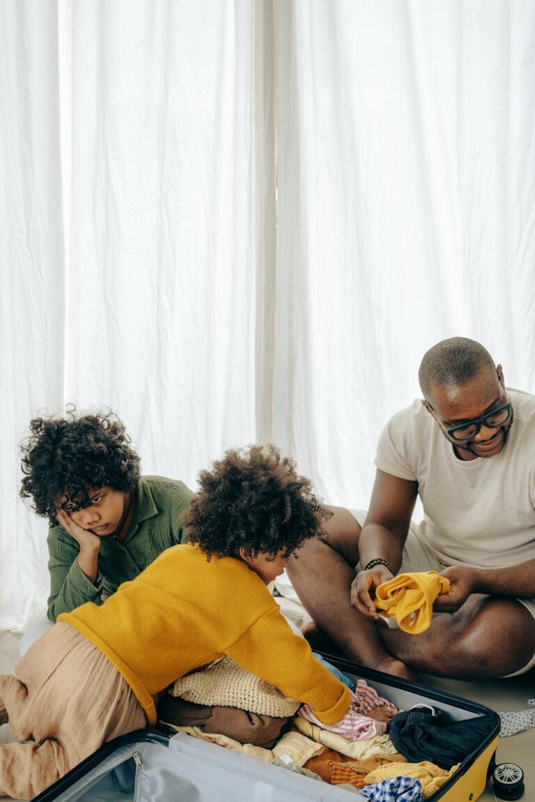 Family packing clothes for a trip, choosing coordinated pieces for family outfits for theme park vacations while sitting around an open suitcase.