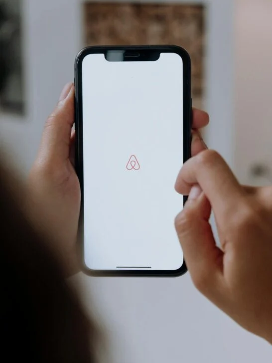 Opening the Airbnb app on a smartphone, a common first step when researching Airbnb hosting tips and listing a propert