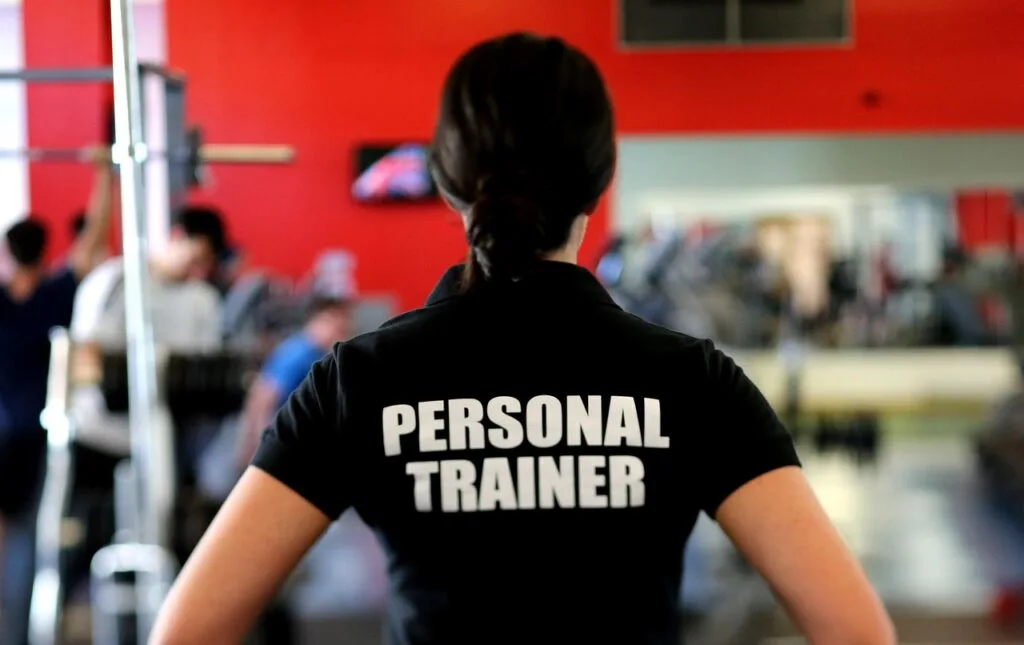 Personal trainer coaching a client through strength exercises in a gym, showing the benefits of hiring a personal trainer for proper form and accountability