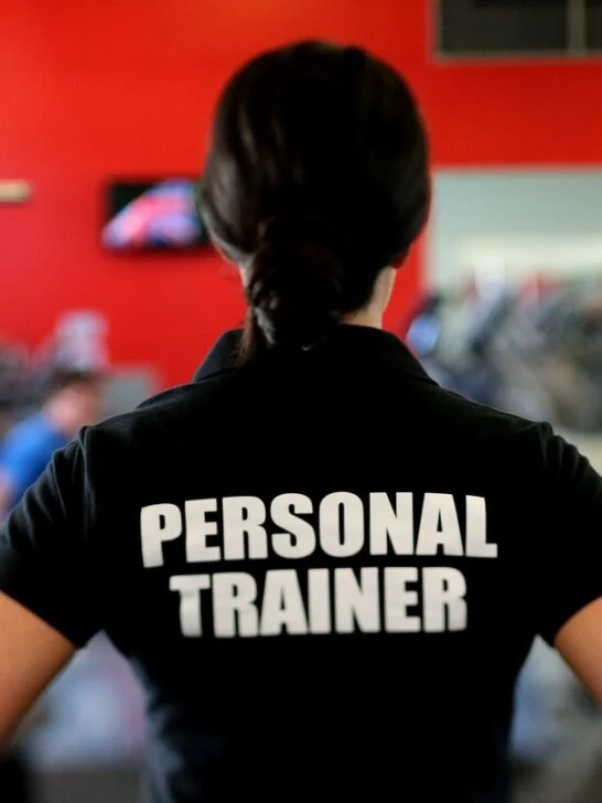 Personal trainer coaching a client through strength exercises in a gym, showing the benefits of hiring a personal trainer for proper form and accountability