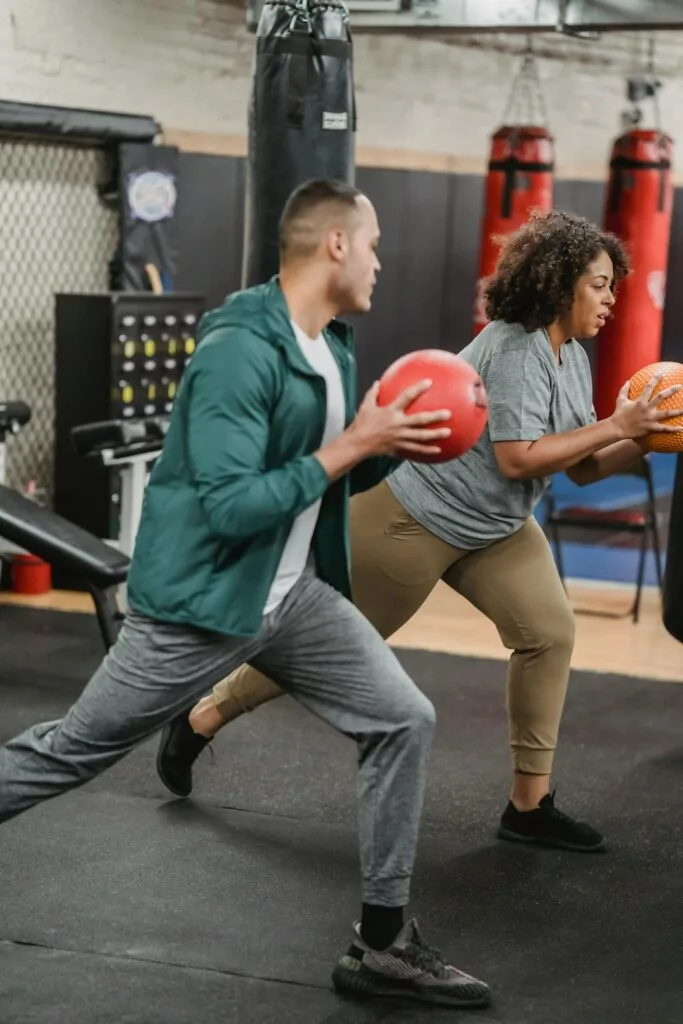 Personal trainer leading a small group workout using medicine balls in a gym setting, focusing on guided movement and strength training
