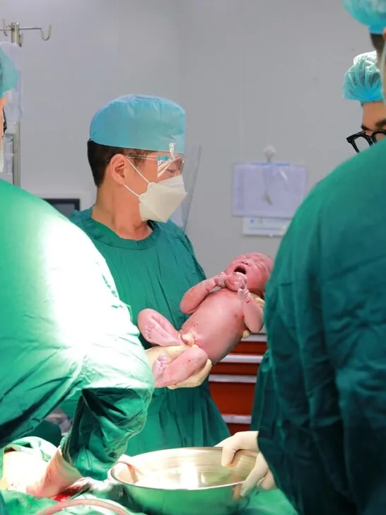 Medical team delivering a newborn in a hospital operating room, highlighting the critical moments involved in birth injury medical malpractice cases.