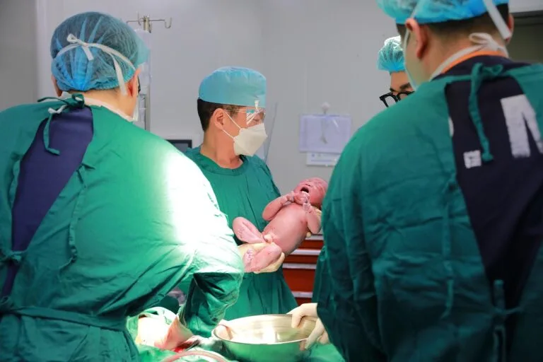 Medical team delivering a newborn in a hospital operating room, highlighting the critical moments involved in birth injury medical malpractice cases.