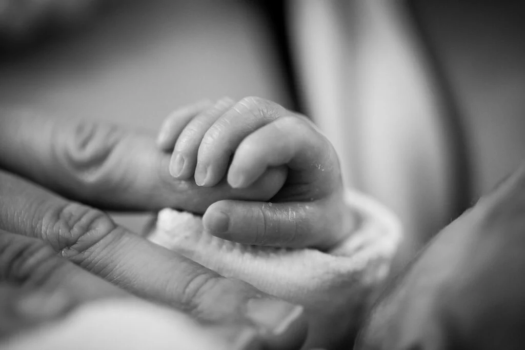 Newborn baby holding an adult&rsquo;s finger