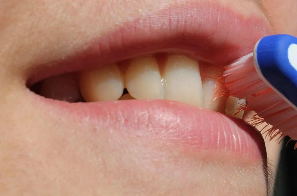 Close-up of a person brushing their teeth near the gumline, showing proper technique as part of a daily oral health routine.