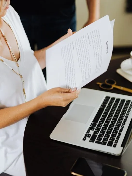 Professional reviewing documents beside a laptop at a desk, showing modern work habits and everyday business communication in action.