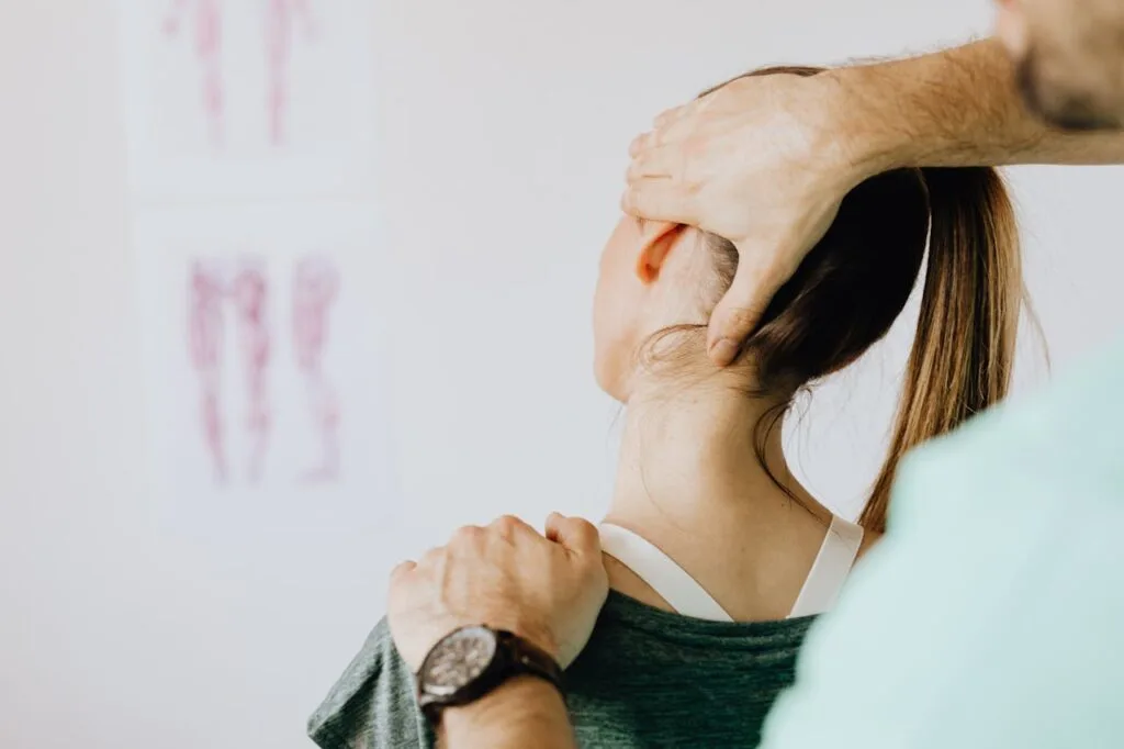A physical therapist gently supporting a woman&rsquo;s neck during treatment, showing how to heal an injury faster with safe hands-on guidance.
