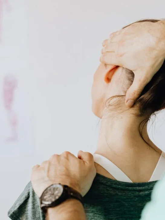 A physical therapist gently supporting a woman’s neck during treatment, showing how to heal an injury faster with safe hands-on guidance.