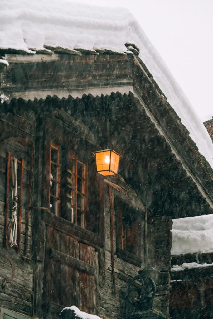 Snow and ice buildup along a house roof edge during winter weather, showing potential roof and gutter stress