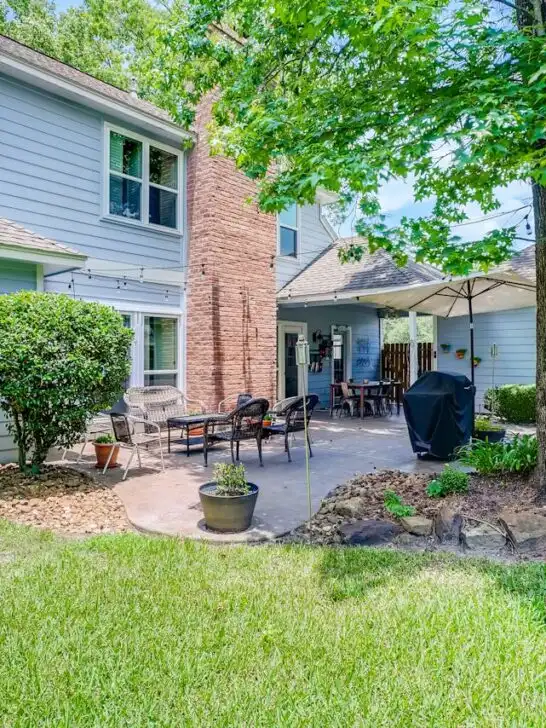 Backyard patio with outdoor seating, greenery, and a clean lawn showcasing simple backyard makeover tips that add comfort and style.