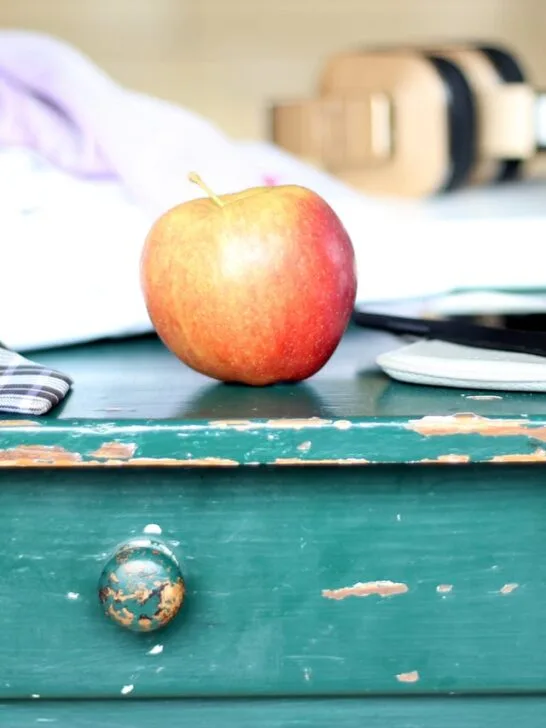 Worn green painted wooden drawer with chipped paint, a red apple on top, and everyday items resting on the surface, showing signs of age and use.
