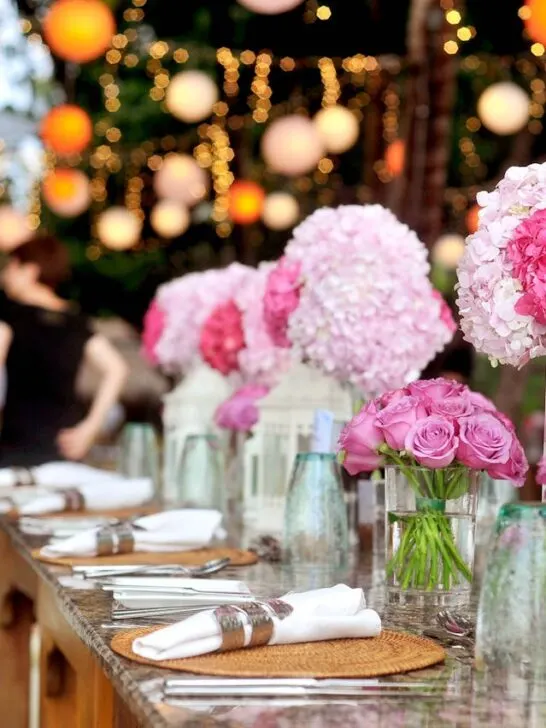 Thoughtful event spaces featuring an outdoor dining setup with soft lighting, pink floral centerpieces, and a warm, inviting atmosphere for a special occasion.