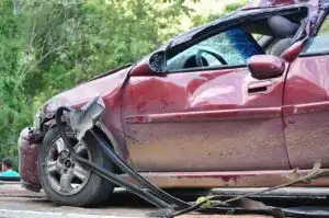 Close view of a red car with severe rear side damage and deployed airbag during an accident reconstruction investigation documenting impact forces